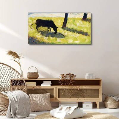 A cow grazing in a green landscape Canvas print