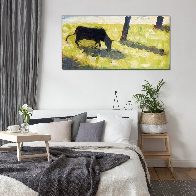 A cow grazing in a green landscape Glass Wall Art
